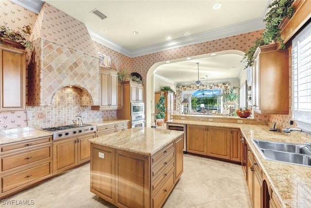 kitchen with sink, crown molding, a center island, appliances with stainless steel finishes, and light stone countertops