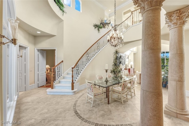 entrance foyer with ornate columns, crown molding, a towering ceiling, and a notable chandelier