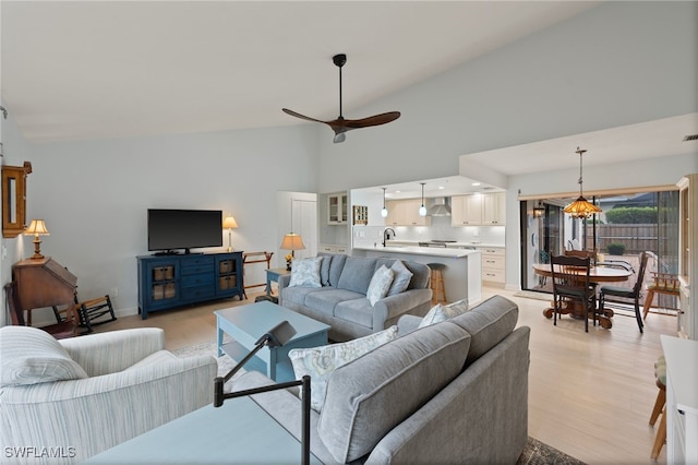 living room featuring light hardwood / wood-style floors, high vaulted ceiling, sink, and ceiling fan