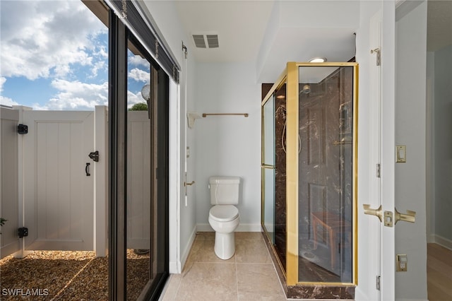 bathroom with tile patterned floors, toilet, and a shower with door