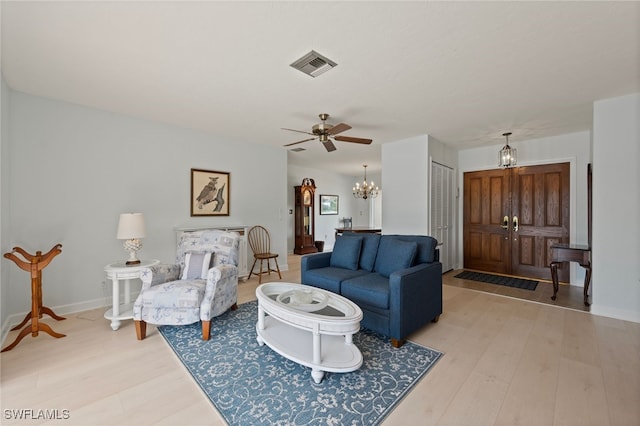 living room with light wood-type flooring and ceiling fan with notable chandelier