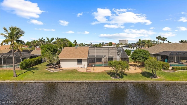 back of property with a yard, a water view, and glass enclosure