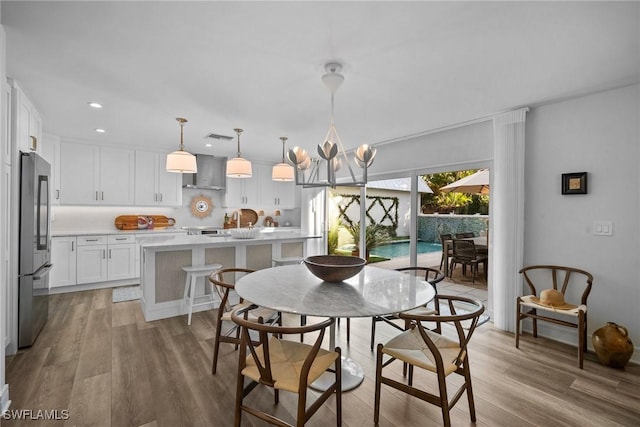 dining area with light wood finished floors, recessed lighting, visible vents, and an inviting chandelier