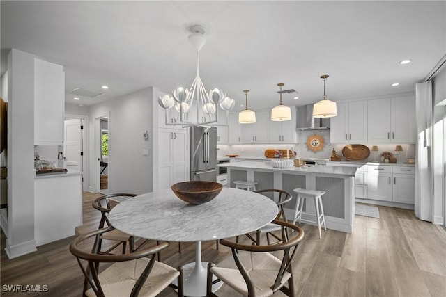 dining room with light wood-style floors, a notable chandelier, and recessed lighting