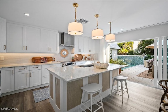 kitchen featuring light wood-style flooring, a sink, visible vents, wall chimney range hood, and stainless steel electric stove