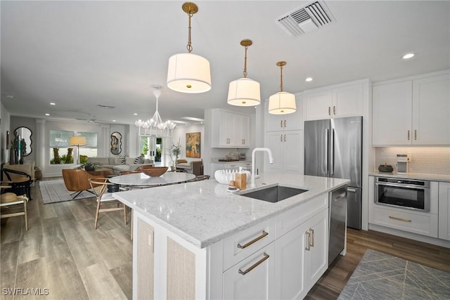 kitchen featuring stainless steel appliances, wood finished floors, a sink, visible vents, and open floor plan