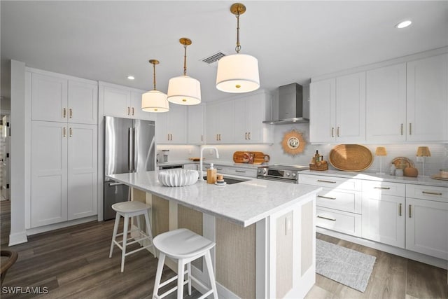 kitchen with stainless steel appliances, a sink, visible vents, wall chimney range hood, and dark wood-style floors