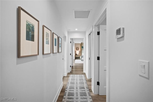 hallway with dark wood-style flooring, visible vents, and baseboards