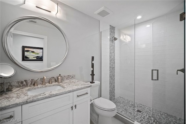 bathroom featuring toilet, a stall shower, visible vents, and vanity