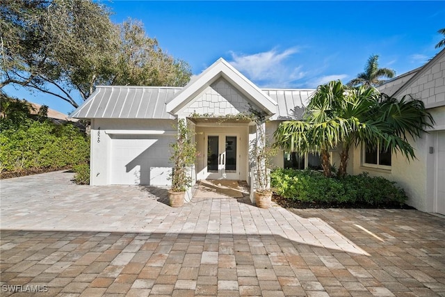 view of front of home with a garage, french doors, metal roof, and a standing seam roof