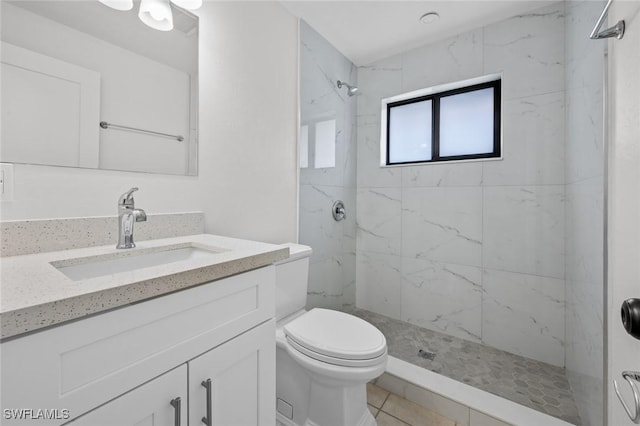 bathroom with vanity, toilet, and a tile shower