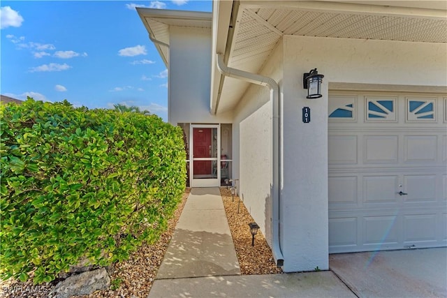 property entrance featuring a garage and stucco siding