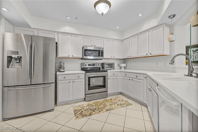 kitchen featuring stainless steel appliances, decorative light fixtures, sink, and white cabinets