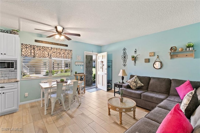 living area featuring ceiling fan, a textured ceiling, light wood-type flooring, and baseboards