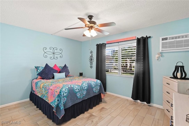 bedroom featuring wood finish floors, a wall mounted air conditioner, a textured ceiling, and baseboards