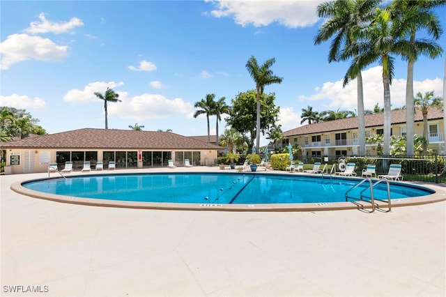 community pool with a patio area and fence