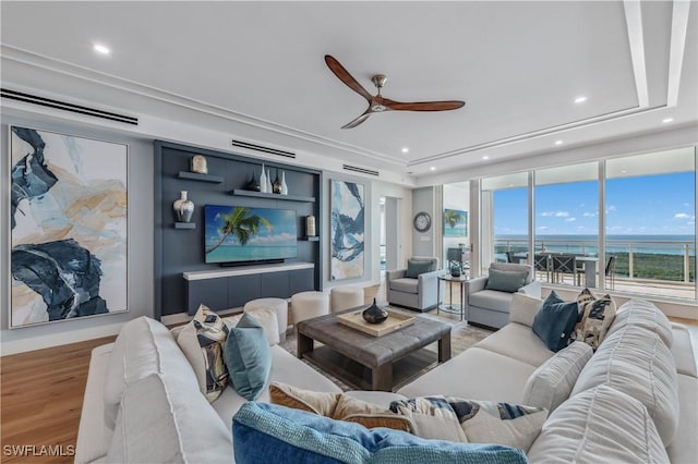 living room with ceiling fan, a tray ceiling, and hardwood / wood-style floors