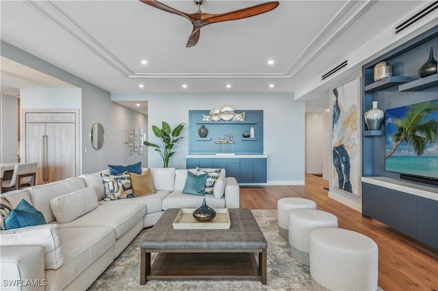 living room featuring a tray ceiling, wood-type flooring, and ceiling fan