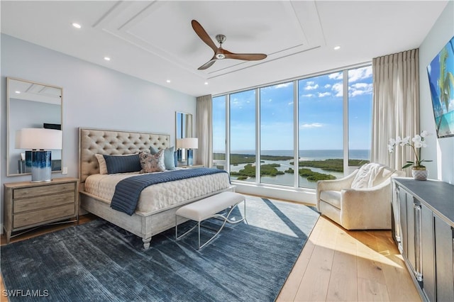 bedroom with expansive windows, hardwood / wood-style flooring, access to outside, and ceiling fan