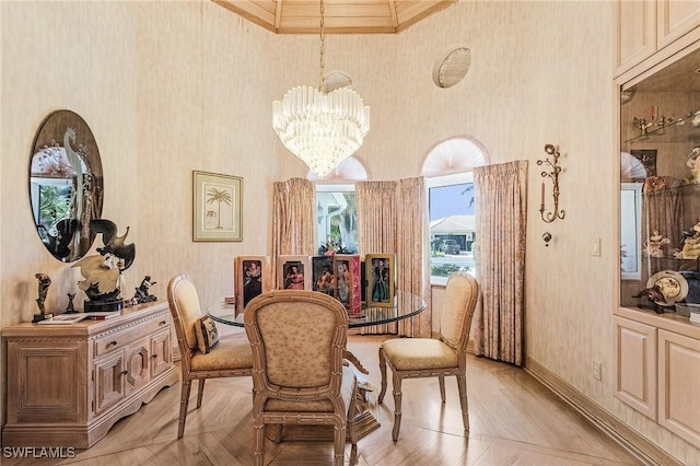 dining area with baseboards, wallpapered walls, a high ceiling, and an inviting chandelier