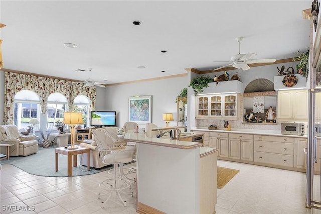 kitchen featuring light countertops, a breakfast bar, stainless steel microwave, and a ceiling fan