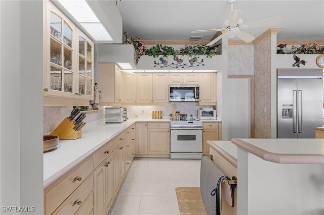 kitchen featuring stainless steel appliances, light countertops, glass insert cabinets, and decorative backsplash