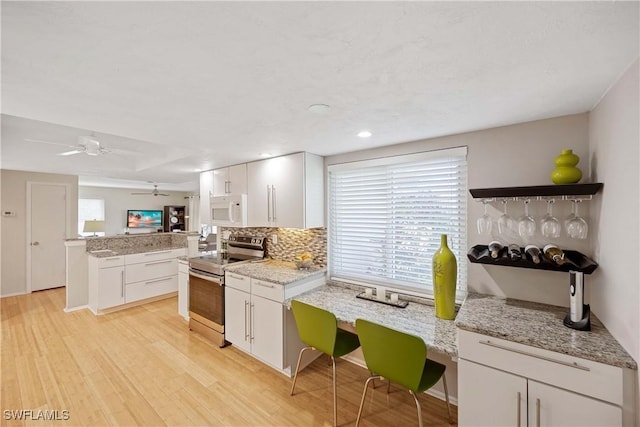 kitchen with backsplash, light hardwood / wood-style floors, white cabinets, stainless steel electric range oven, and kitchen peninsula