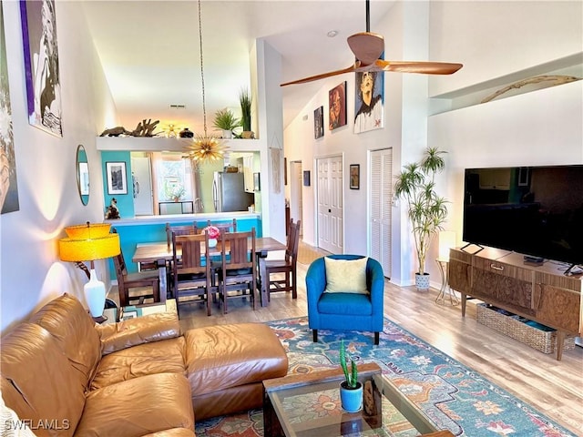 living room featuring a towering ceiling, light hardwood / wood-style floors, and ceiling fan