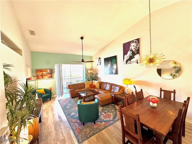 dining area featuring ceiling fan with notable chandelier, light hardwood / wood-style flooring, and high vaulted ceiling