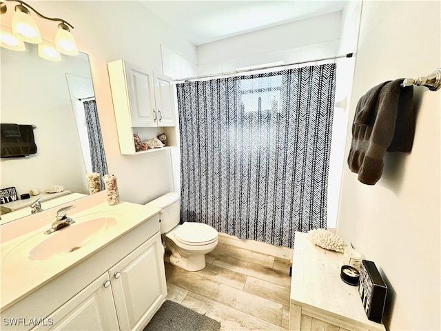 bathroom with hardwood / wood-style flooring, vanity, a shower with shower curtain, and toilet