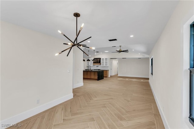 unfurnished living room featuring recessed lighting, ceiling fan with notable chandelier, a sink, baseboards, and vaulted ceiling