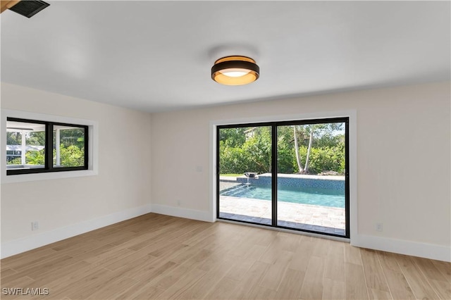 unfurnished room featuring baseboards, light wood-style flooring, and a healthy amount of sunlight