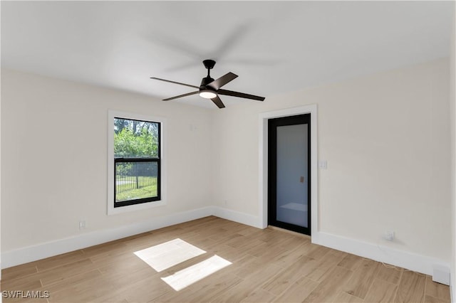 spare room with baseboards, ceiling fan, and light wood-style floors