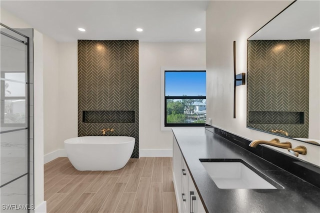 bathroom featuring a soaking tub, tile walls, vanity, and recessed lighting