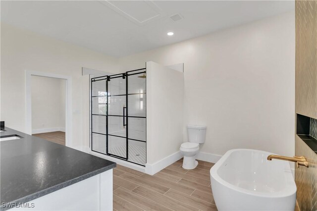 bathroom featuring baseboards, tiled shower, toilet, a soaking tub, and wood finish floors