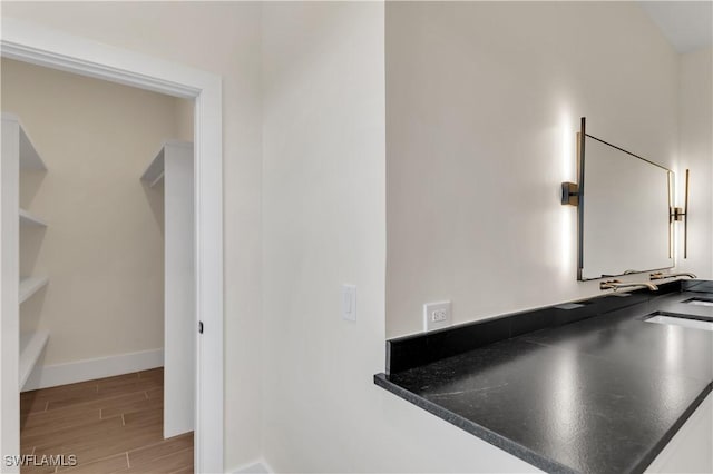 interior details featuring a sink, wood finished floors, and baseboards