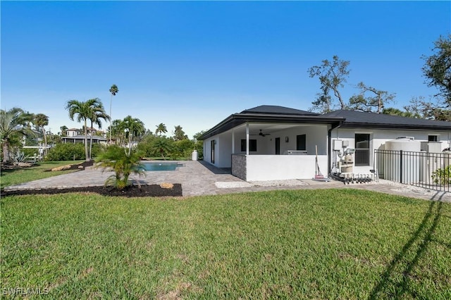 back of property with a patio area, ceiling fan, a yard, and stucco siding