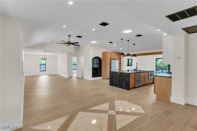 kitchen with lofted ceiling, a sink, open floor plan, stainless steel dishwasher, and freestanding refrigerator