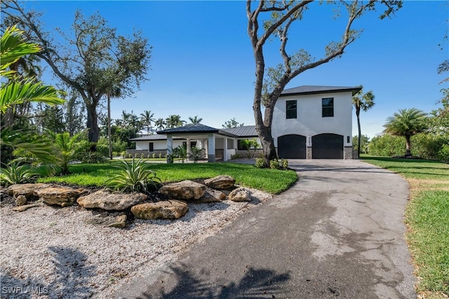 view of front facade featuring aphalt driveway, a garage, stone siding, stucco siding, and a front lawn