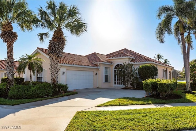 mediterranean / spanish home with stucco siding, an attached garage, a tile roof, and driveway