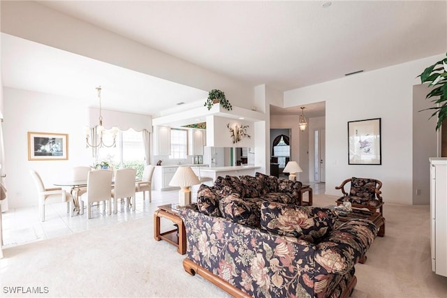living area with a chandelier, visible vents, and light colored carpet