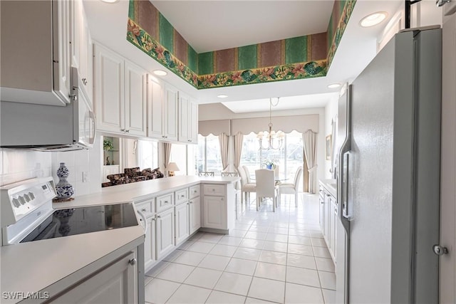kitchen featuring an inviting chandelier, backsplash, white appliances, light countertops, and light tile patterned floors