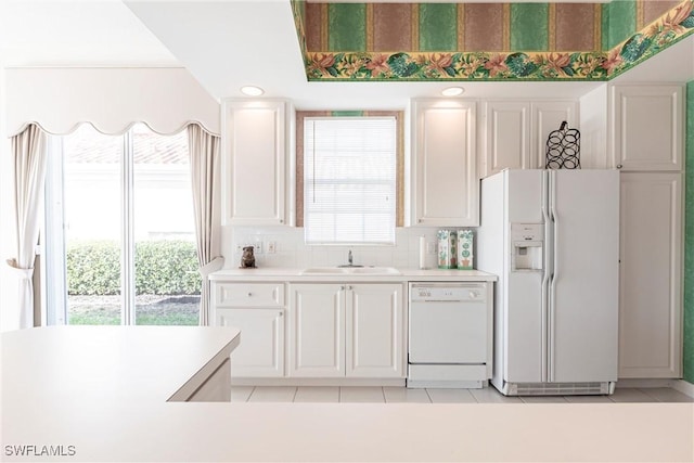 kitchen with a sink, light tile patterned flooring, white appliances, light countertops, and white cabinetry
