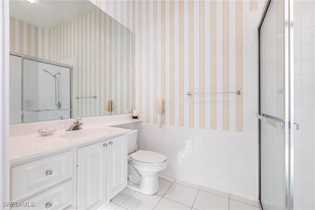 bathroom featuring a shower with shower door, tile patterned floors, toilet, vanity, and wainscoting