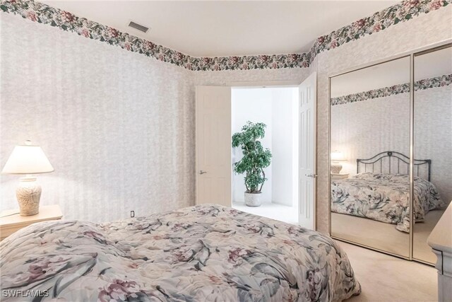 bedroom featuring a closet, visible vents, light colored carpet, and wallpapered walls