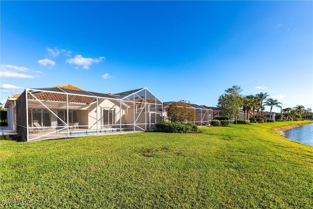 rear view of property featuring glass enclosure, a yard, a water view, and an outdoor pool