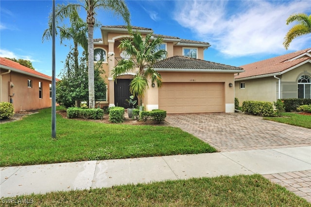 mediterranean / spanish-style house featuring a front yard, decorative driveway, an attached garage, and stucco siding