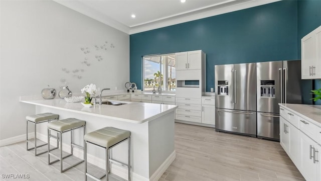 16768 Elkhorn Coral Dr, North Fort Myers, FL 33903 - kitchen with stainless steel fridge with ice dispenser, a sink, a kitchen bar, white cabinetry, and recessed lighting
