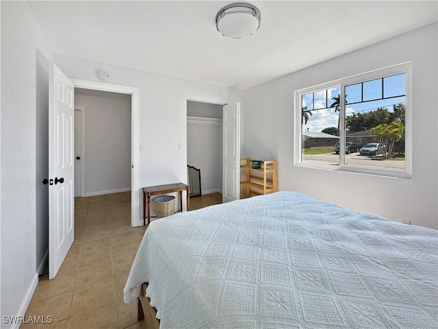 bedroom featuring a closet, light tile patterned flooring, and baseboards