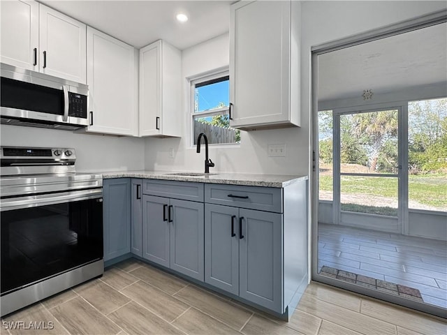 kitchen featuring appliances with stainless steel finishes, gray cabinetry, white cabinetry, a sink, and recessed lighting